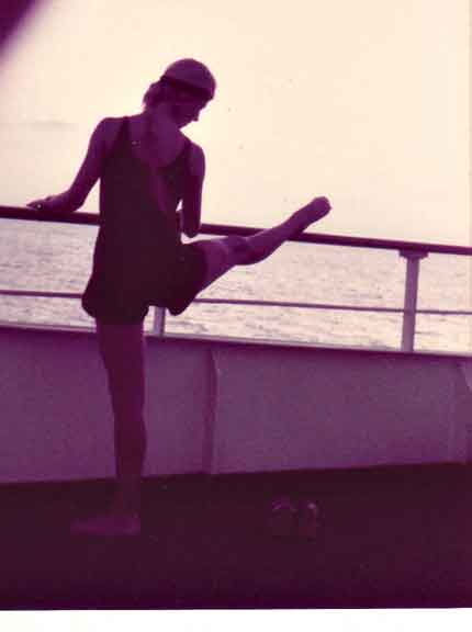 ALT =[“Dr. Jolie Bookspan: Dr. Bookspan pioneered teaching fitness on cruise ships. Pictured here teaching the difference between a turned-out leg for art forms like dance, and the better healthier stretch of keeping the standing leg facing forward.] 